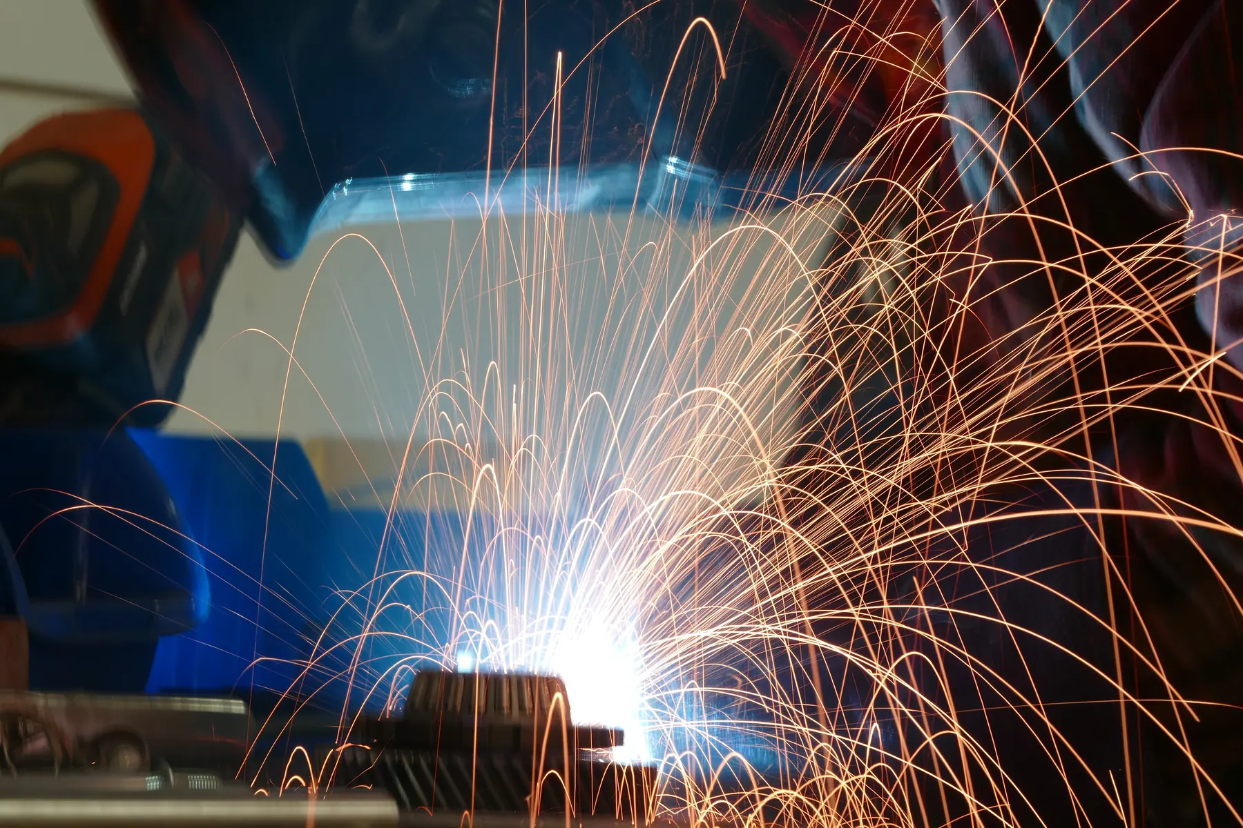Sparks flying as a gear is welded at the workbench